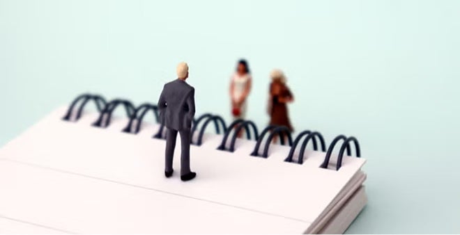 Three miniature business figure figurines standing on spiral bound notebook depicting team meeting or collaboration concept