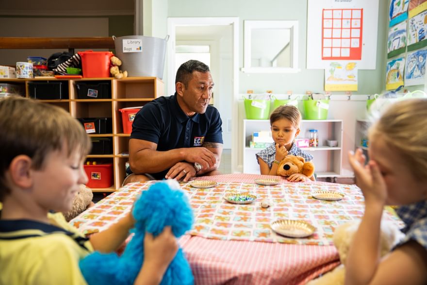 An ECU Master of Education graduate sits in an early childhood classroom, talking to one of the children next to him as they do an activity together.
