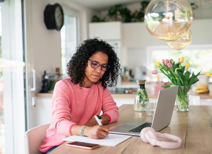 Woman working from home, focused on her laptop, surrounded by a cozy home office environment.