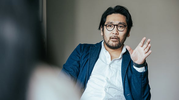 A man wearing glasses is engaged in conversation with another person.