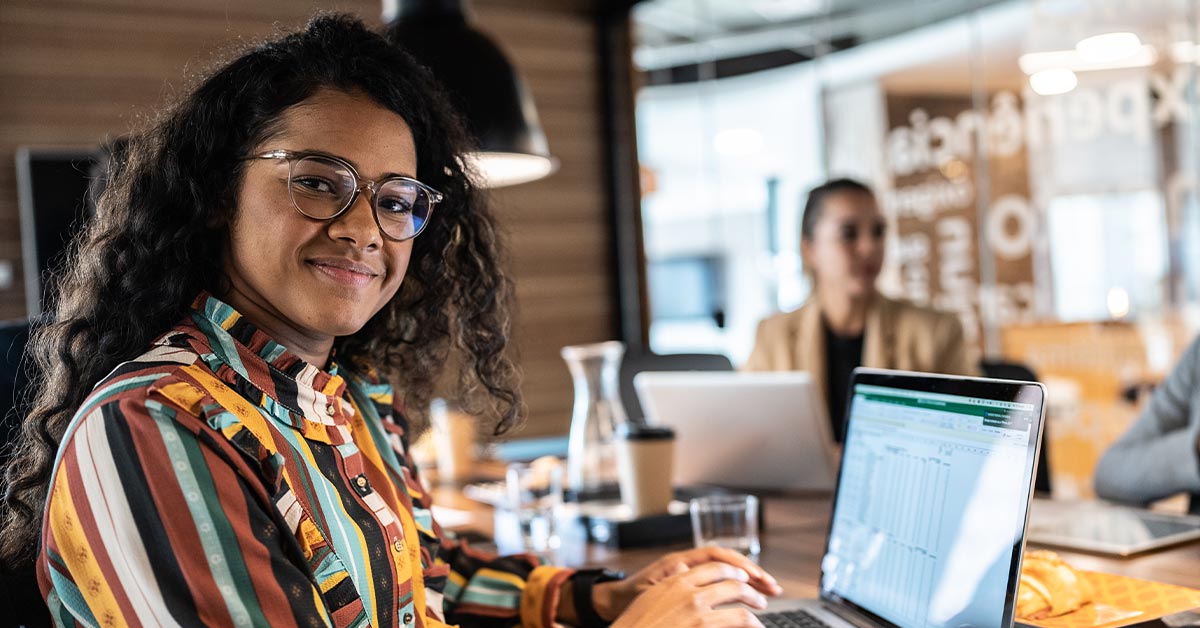 Woman in glasses working on laptop.