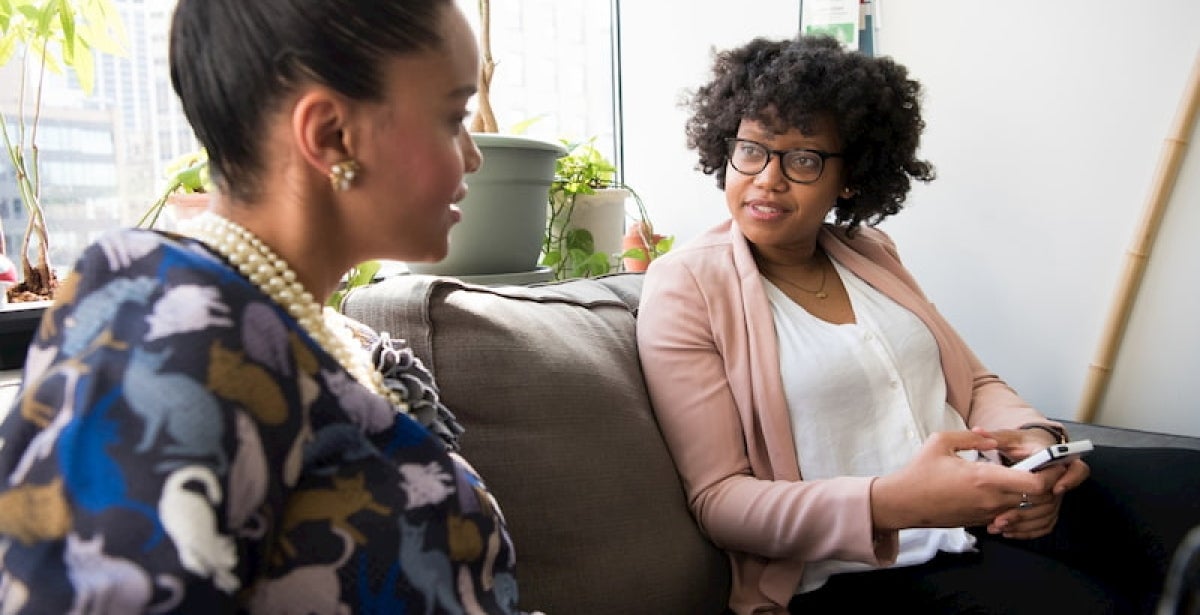 A counsellor and her client are sitting on a couch, the client is talking and the counsellor is listening intently.