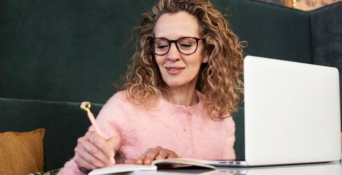 Middle-aged woman writing on a notebook.