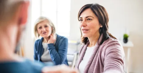 Woman in pink striped cardigan smiling warmly during group counseling session in bright office setting