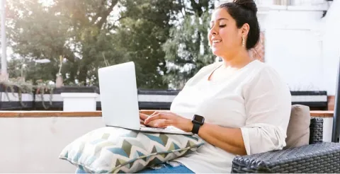 Woman using laptop outdoors on patio in natural setting